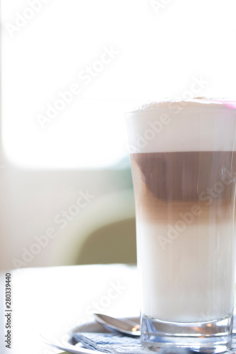 latte macchiato with cocoa powder and coffee beans on white background