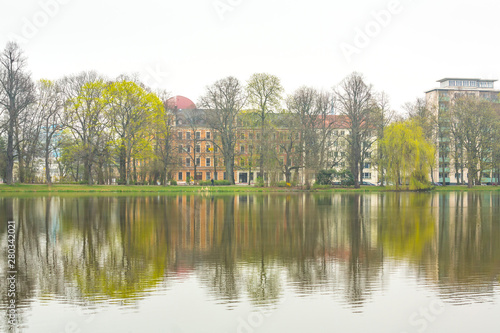 Public park lake in the city. The peaceful water reflects the building that surround the park
