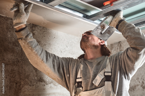 Valokuva Construction worker plastering gypsum walls inside the house.