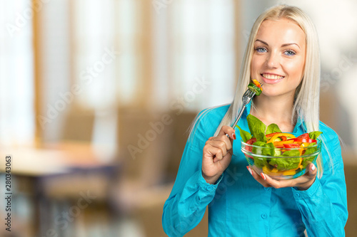 Portrait of a happy playful girl eating fresh salad from a bowl
