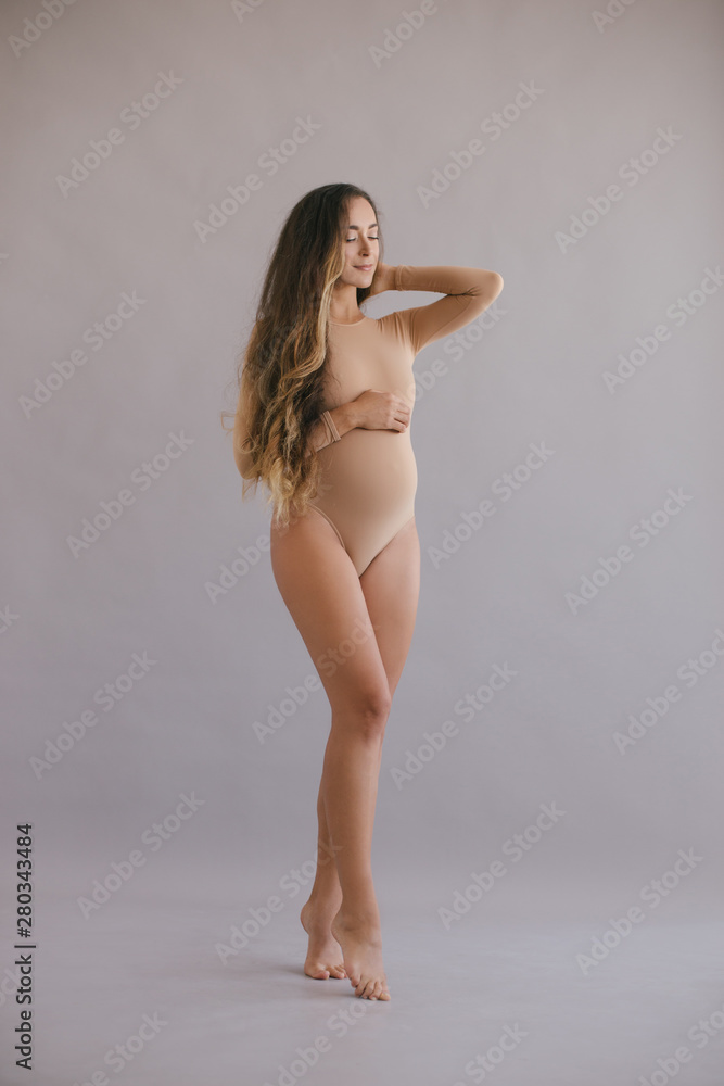 Beautiful pregnant woman with long hair on grey background Beautiful pregnant woman with long hair on grey background