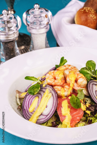 Mediterranean salad. grilled prawns, red onion rings, lemon peel, ginger root and vegetables dressed with olive oil