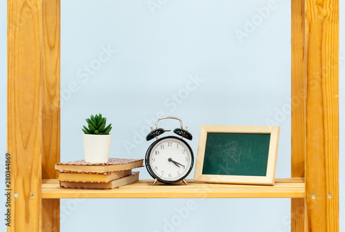 Wooden shelf with alarm clock and objects against blue background