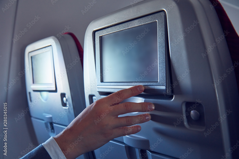 Man using touchscreen in modern airplane seat. Man using touchscreen in modern airplane seat.