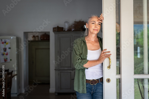 Mature woman thinking at home entrance