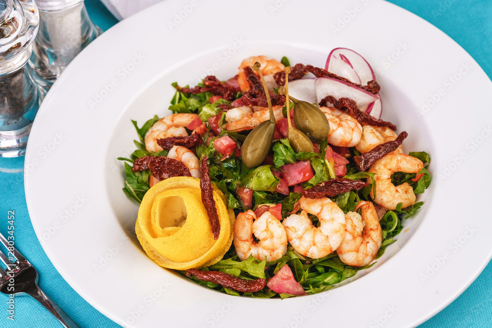Mediterranean salad. Arugula, tomatoes, shrimps, olives, olives, basil and rosemary, dressed with olive oil and balsamic sauce, decorated with lemon and chili pepper Mediterranean salad. Arugula, tomatoes, shrimps, olives, olives, basil and rosemary, dressed with olive oil and balsamic sauce, decorated with lemon and chili pepper