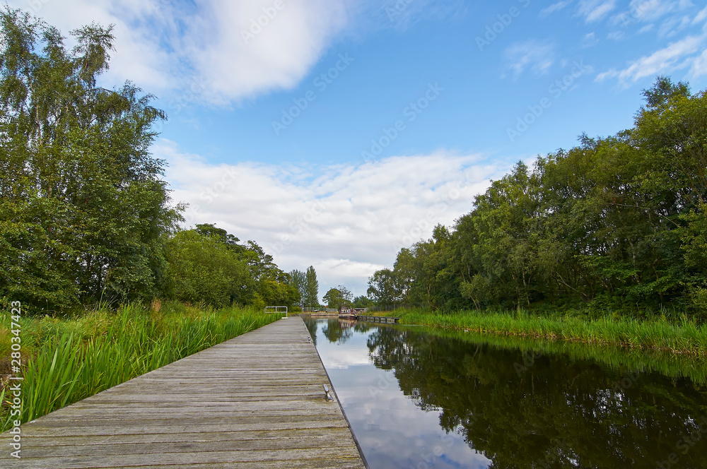 The Forth and Clyde canal, part of Scotlands waterways Heritage near the Falkirk Wheel with Narrow Boats moored along the Bank in the distance, Falkirk, Scotland.