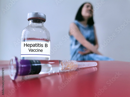Bottle of Hepatitis B vaccine (selective focus) for injection and blurred background of woman. This vaccine used for protection and immunization from hepatitis B virus (HBV) infection. Medical vaccine photo