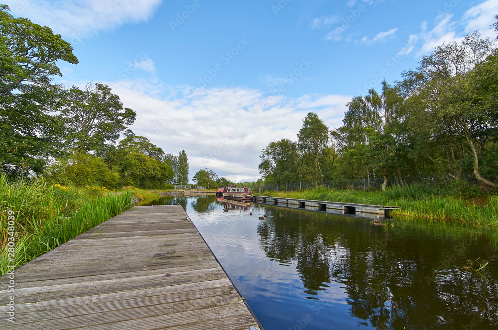 The Forth and Clyde canal, part of Scotlands waterways Heritage near the Falkirk Wheel with Narrow Boats moored along the Bank in the distance, Falkirk, Scotland. The Forth and Clyde canal, part of Scotlands waterways Heritage near the Falkirk Wheel with Narrow Boats moored along the Bank in the distance, Falkirk, Scotland.