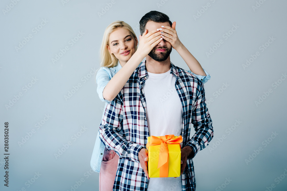 Εκτύπωση καμβά beautiful girl Covering Eyes of man holding present on grey