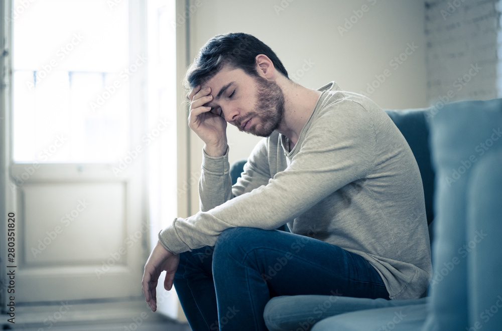 Young man suffering from depression hopeless and alone at home - obrazy, fototapety, plakaty 