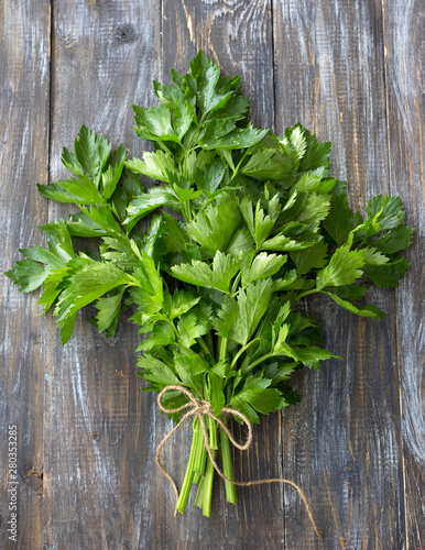 Bunch of fresh organic celery on a wooden background, top view
