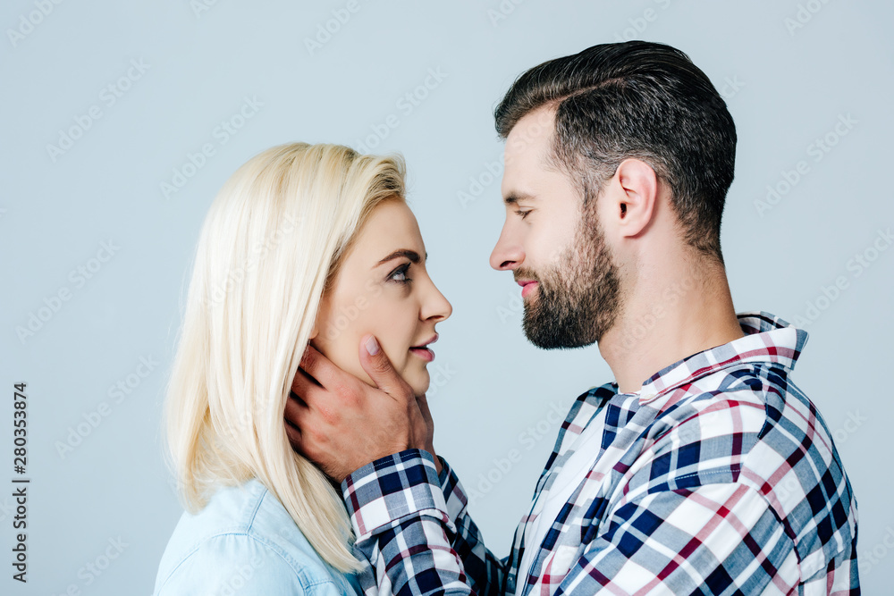 handsome man embracing face of beautiful young woman isolated on grey handsome man embracing face of beautiful young woman isolated on grey