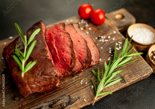 Fresh beef steak, herbs and spices on a stone background