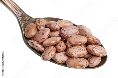 In the old golden spoon there is a small pile of food - dry brown spotted beans isolated macro