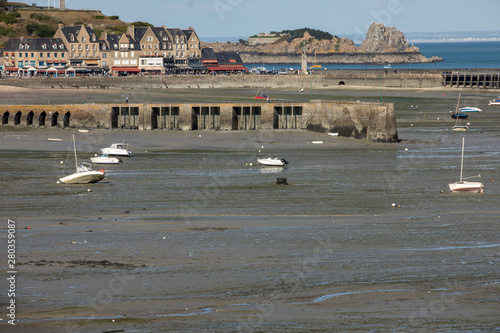 Boats on dry land at the beach at low tide in Cancale famous oysters production town, Brittany, France,