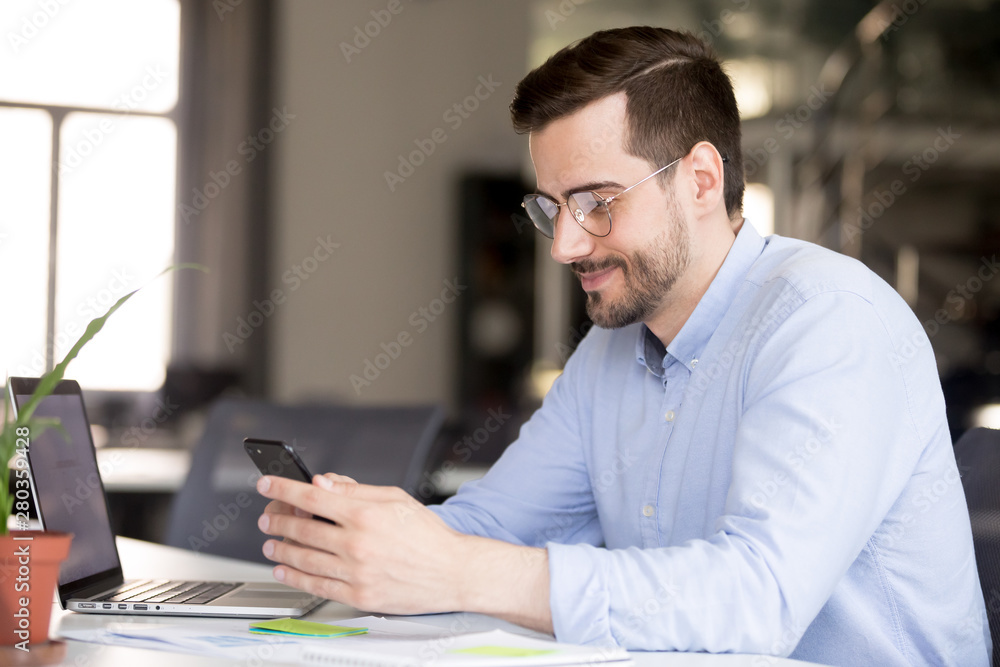 Satisfied businessman using mobile phone at workplace Satisfied businessman using mobile phone at workplace