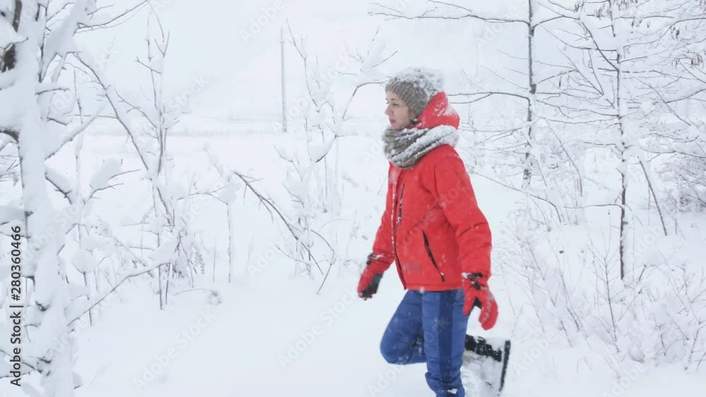 A woman wades through the snow and branches of trees in winter forest. A woman wades through the snow and branches of trees in winter forest.
