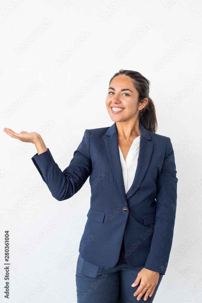 Content businesswoman showing copy space. Beautiful happy young woman gesturing with hand and smiling at camera isolated on grey background. Emotion concept Content businesswoman showing copy space. Beautiful happy young woman gesturing with hand and smiling at camera isolated on grey background. Emotion concept