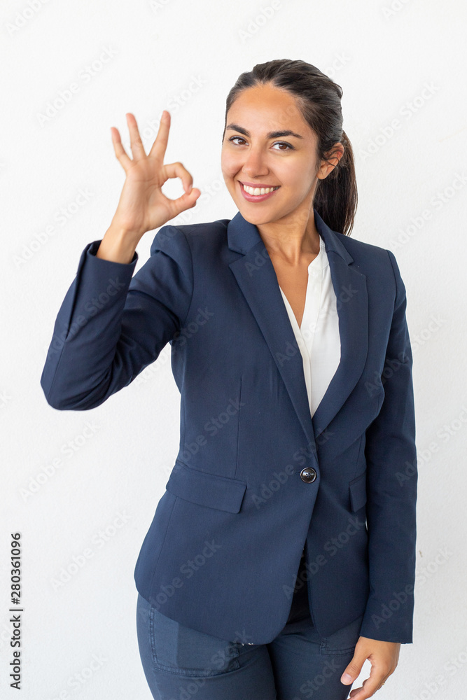 Happy businesswoman showing ok sign. Beautiful young woman showing ok sign and smiling at camera isolated on grey background. Gesture concept Happy businesswoman showing ok sign. Beautiful young woman showing ok sign and smiling at camera isolated on grey background. Gesture concept