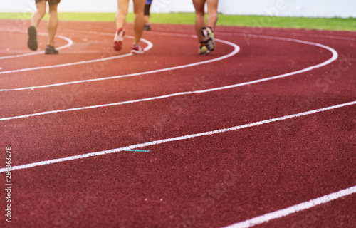 blur group of athlete legs on red running tract white curve line of sport stadium background