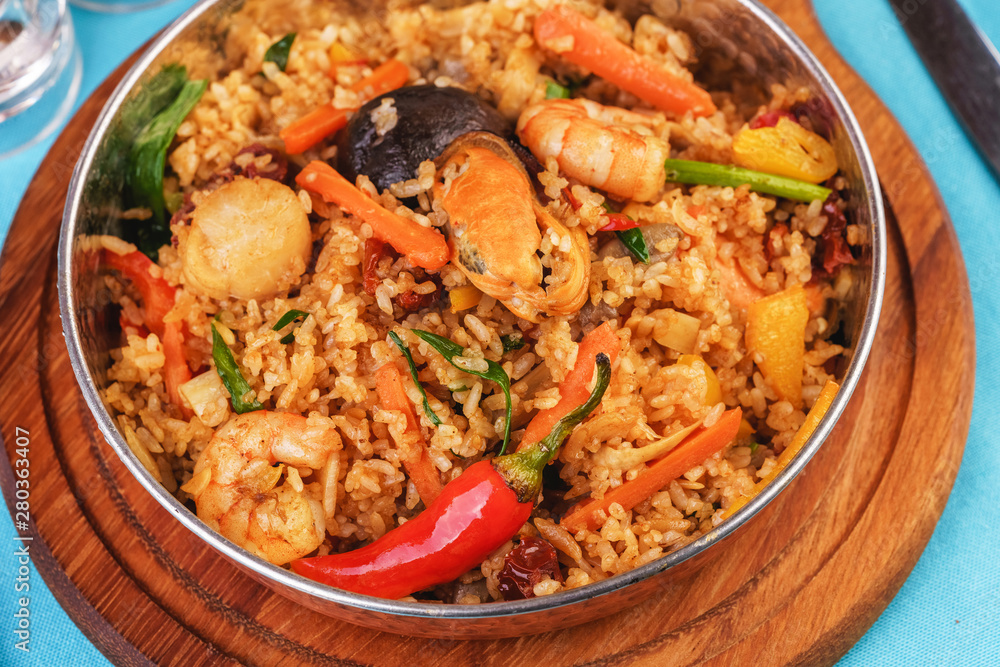 Mediterranean dish, European cuisine. The dish is from Uzbek cuisine. Rice fried with vegetables - greens, carrots, red pepper, onions and seafood - shrimps, mussels and squid. Mediterranean dish, European cuisine. The dish is from Uzbek cuisine. Rice fried with vegetables - greens, carrots, red pepper, onions and seafood - shrimps, mussels and squid.