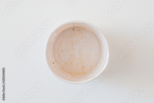 Empty dirty paper cup with the lees (leavings) of ice cream. Garbage, recyclable and unprocessed waste concept. Banner, copy space. Soft focus on white flat lay background.