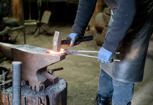 A blacksmith forges iron parts. A man at work. Forge, hot metal
