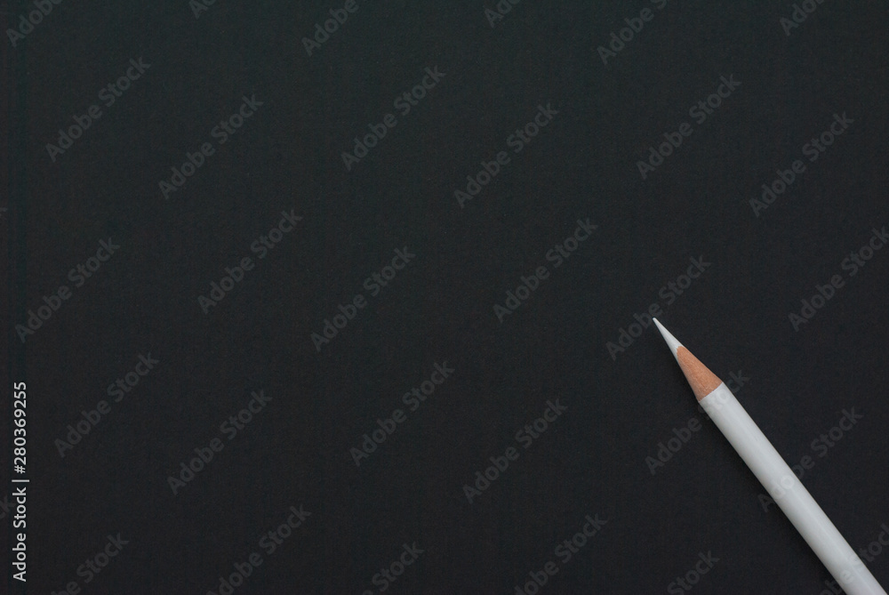White (chalk) pencil lies diagonally on black paper. School, business  template or blank. Stock Photo