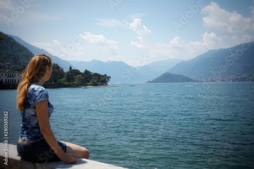 Girl sitting and looking on the Lake Como of Bellagio.