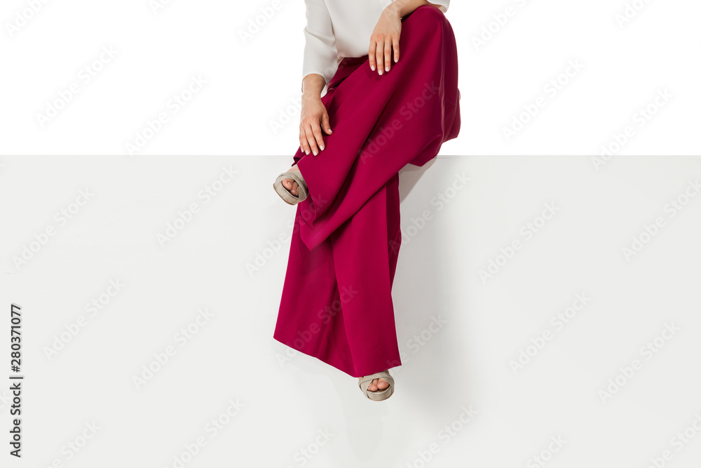 beautiful legs woman wearing burgundy trousers and high heels shoes sitting on white bench. beautiful legs woman wearing burgundy trousers and high heels shoes sitting on white bench.