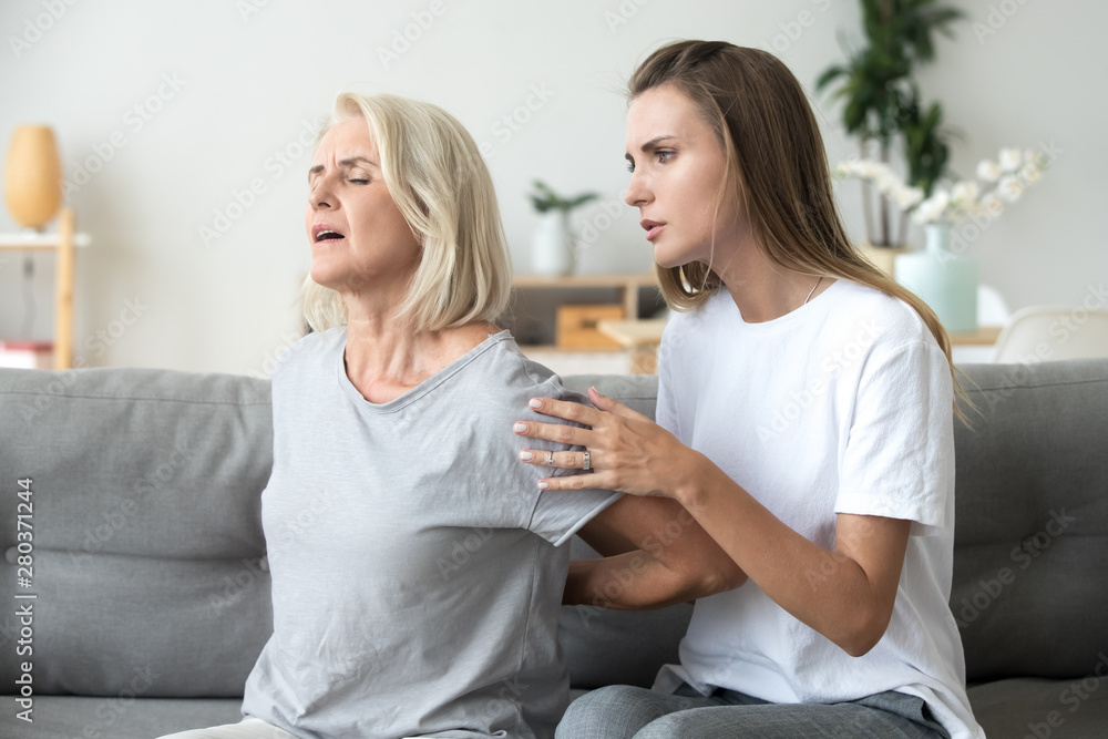 Mother suffering from back pain daughter feeling worry Mother suffering from back pain daughter feeling worry