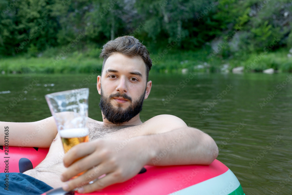 Leisure concept, holiday, weekend. bearded man of caucasian appearance with glasses of beer on nature, on green and water background Leisure concept, holiday, weekend. bearded man of caucasian appearance with glasses of beer on nature, on green and water background