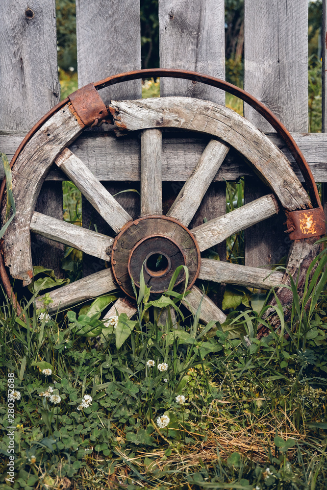 Wooden Wheel standing about Barn Wall