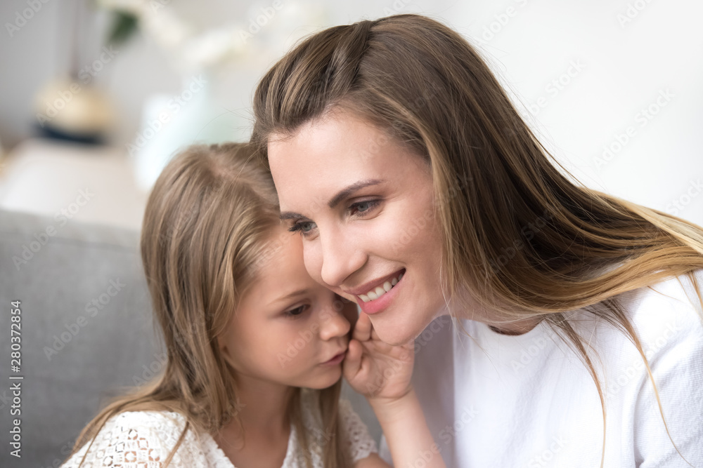 Daughter whispering to moms ear a secret Daughter whispering to moms ear a secret