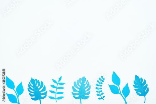 top view of blue paper cut tropical leaves in row isolated on white with copy space