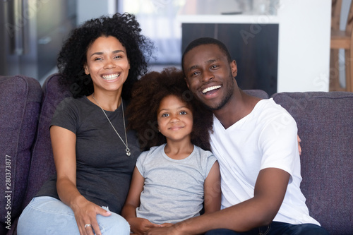 African family and daughter sitting on couch posing for camera