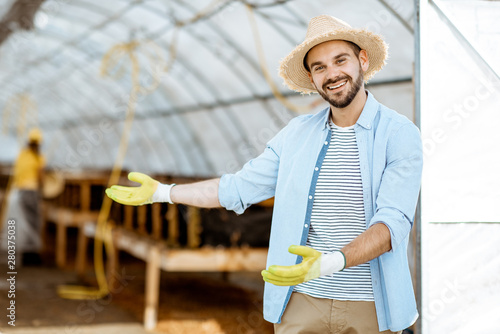 Portrait of a handsome farmer standing in front of the hothouse on a farm with snail breeding outdoors photo