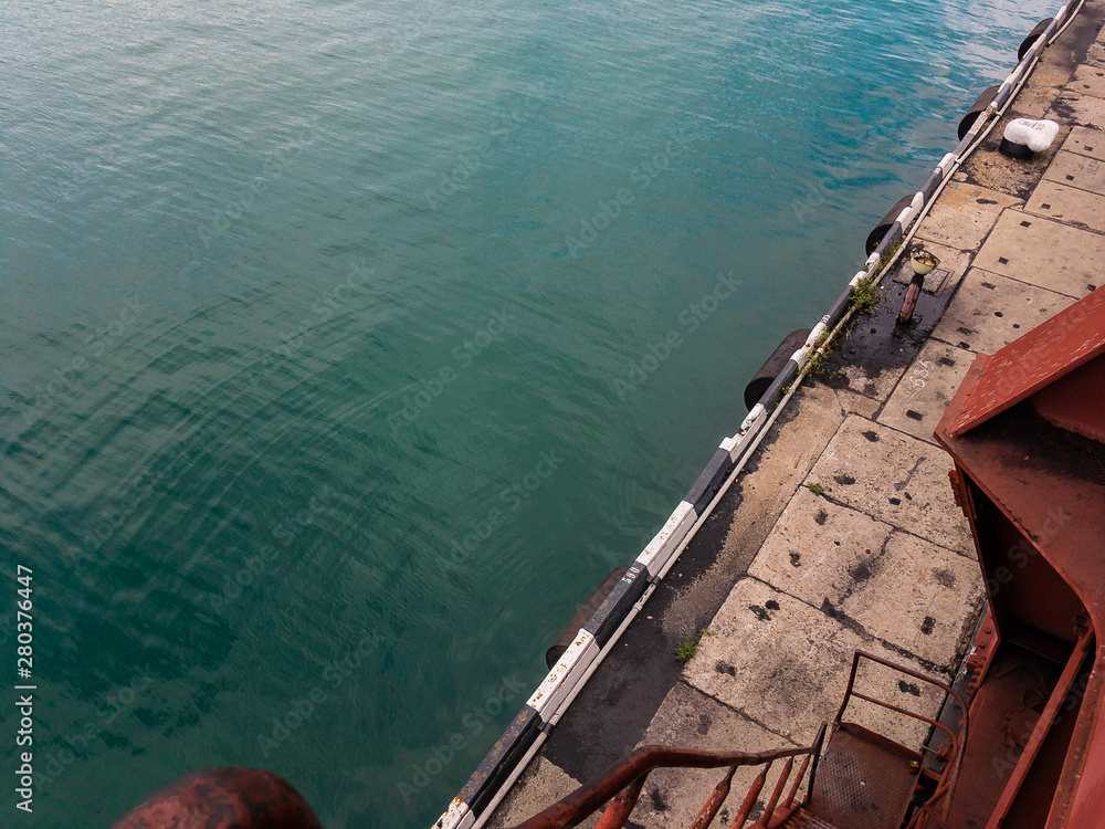Obraz premium View from the portal crane to the pier and turquoise sea water on a sunny summer day.
