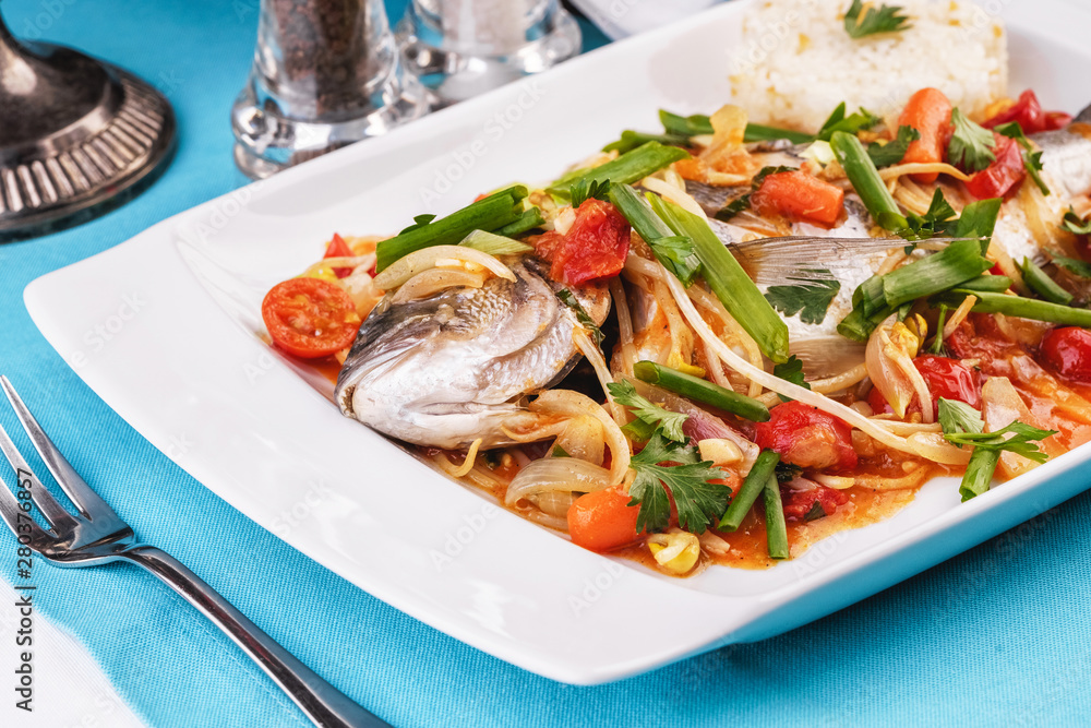 Seafood, Mediterranean cuisine. Baked sea fish with mushrooms, herbs, carrots, millers, cilantro, corn and onions. Caucasian national cuisine Seafood, Mediterranean cuisine. Baked sea fish with mushrooms, herbs, carrots, millers, cilantro, corn and onions. Caucasian national cuisine