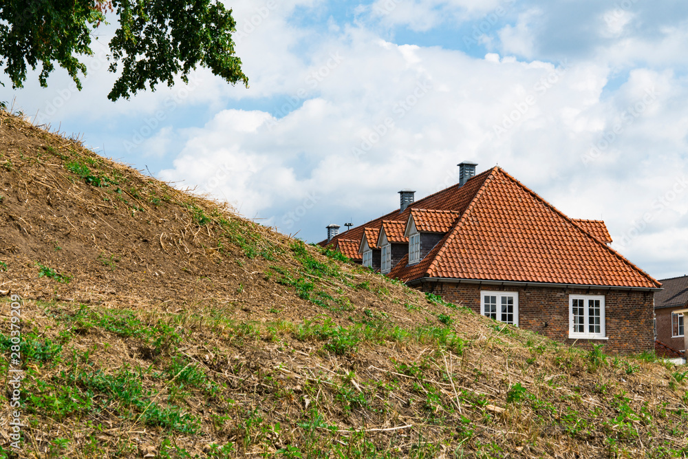 Hill and houses with orange roof tiles and white window. Grave, The Netherlands
