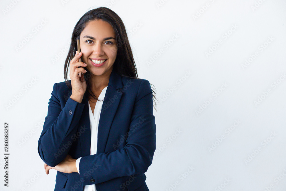 Happy businesswoman talking by smartphone. Attractive young woman in formal wear talking by cell phone and smiling at camera isolated on grey background. Connection concept Happy businesswoman talking by smartphone. Attractive young woman in formal wear talking by cell phone and smiling at camera isolated on grey background. Connection concept