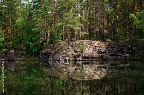 Coniferous forest is reflected in a lake with granite shores