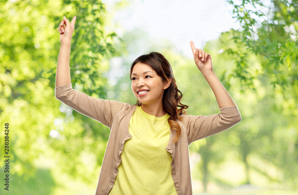 people and leisure concept - happy young asian woman dancing over green natural background people and leisure concept - happy young asian woman dancing over green natural background