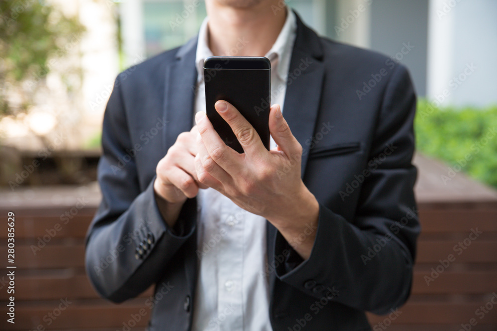 Businessman using app or taking picture on smartphone outside. Man in office holding cellphone. Communication or wireless technology concept Businessman using app or taking picture on smartphone outside. Man in office holding cellphone. Communication or wireless technology concept