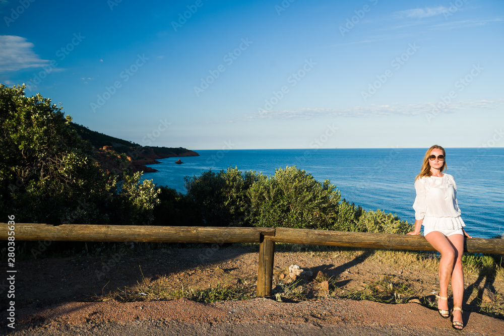 Blonde caucasian woman, aged 30-39, enjoying the beautiful scenic of french rivera near l'esterl mountain ,holiday concept, loving life, ideal for tourism industry. lens flare