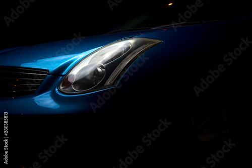  Headlight car. Headlight blue sports car. Part of the blue car on a dark background.