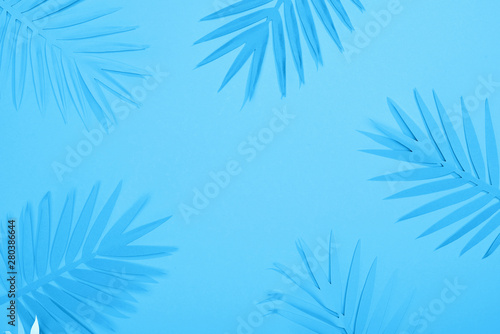 top view of paper leaves on blue minimalistic background with copy space