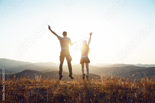 A young couple jumping and having fun. Dawn in the mountains, the beginning of a new day