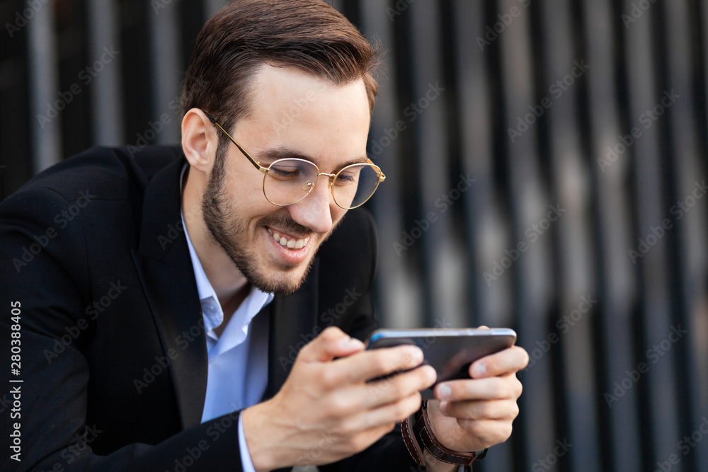 Attractive man smiles and holds smart phone horizontally. Watching video, playing, browsing the Internet. Attractive man smiles and holds smart phone horizontally. Watching video, playing, browsing the Internet.